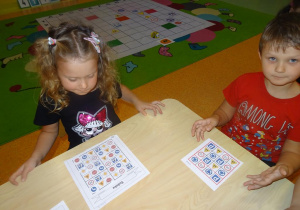 Dwoje dzieci siedzi przy stole i przygląda się ułożonemu sudoku.